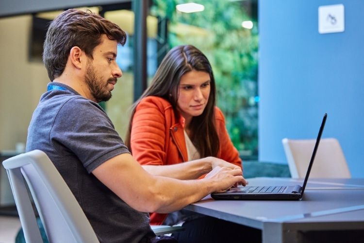 Homem e mulher no trabalho, olhando para o notebook.