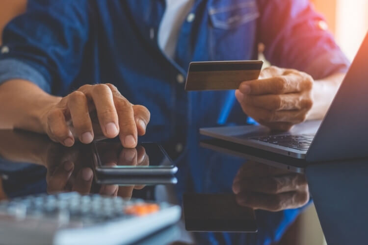 Homem fazendo compra com cartão de crédito pelo celular.