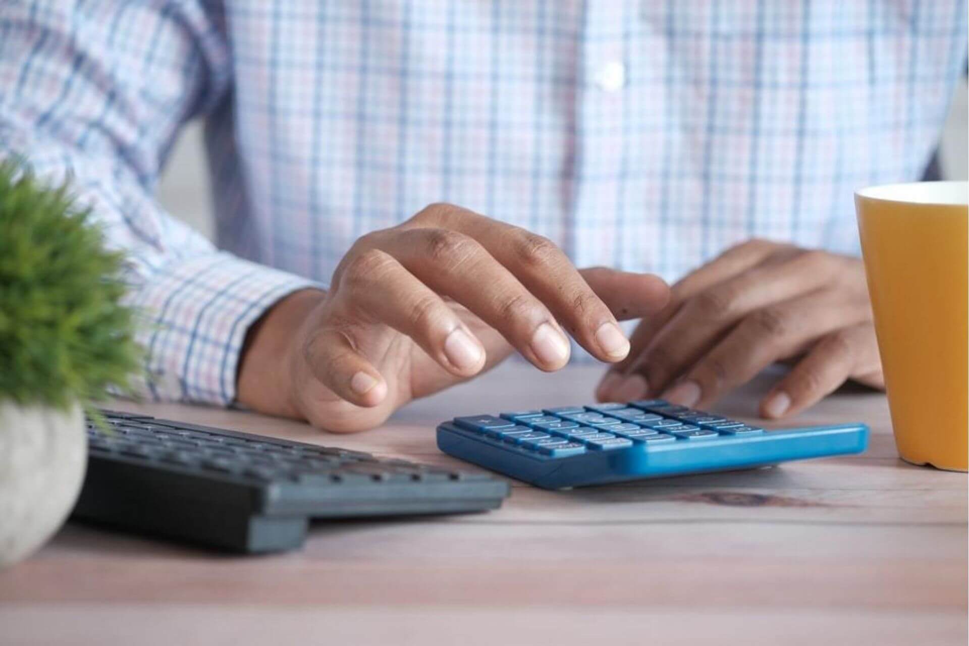 Homem calculando estorno de venda em uma calculadora.