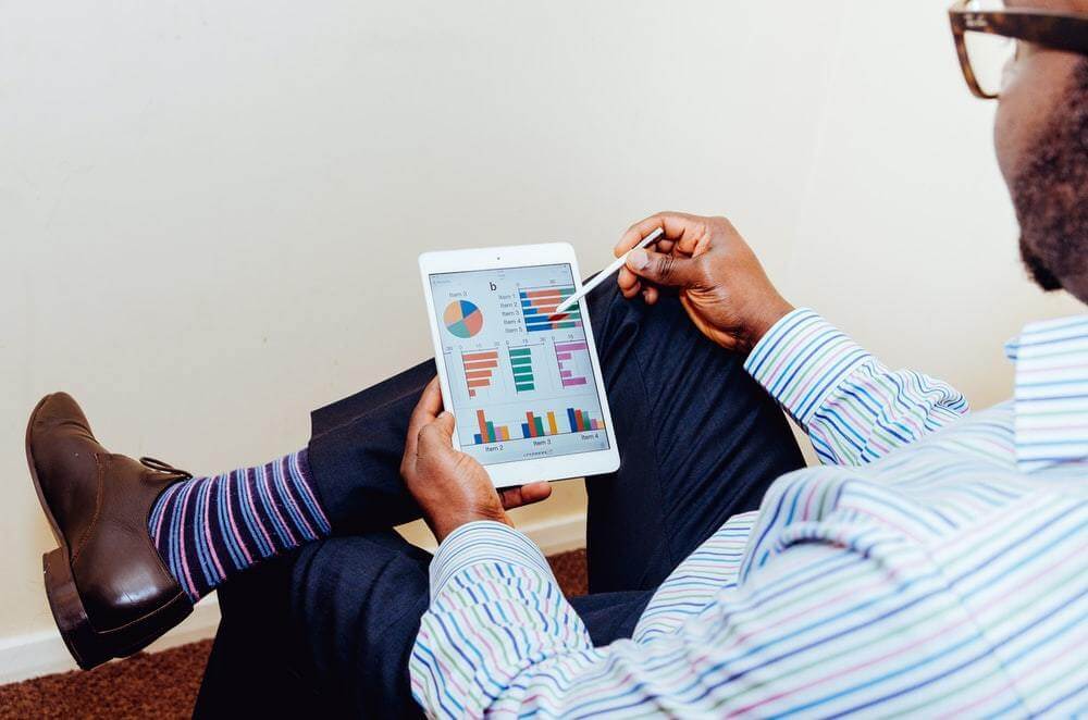 Homem analisando gráficos em um tablet.