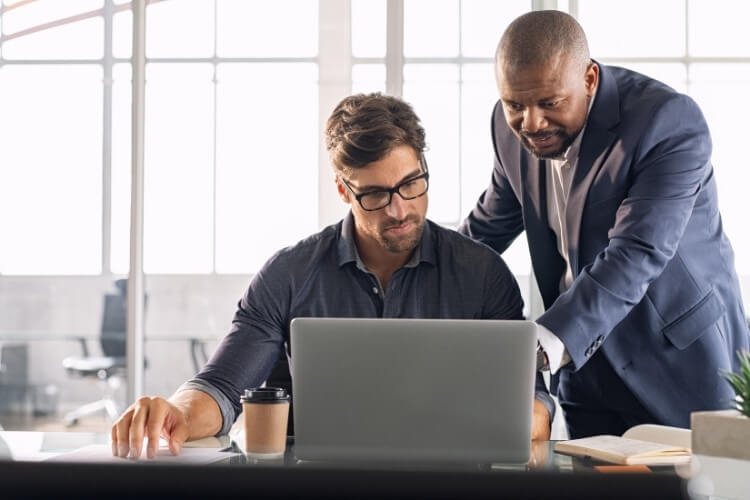 Homens de negócios analisando dados em um notebook.