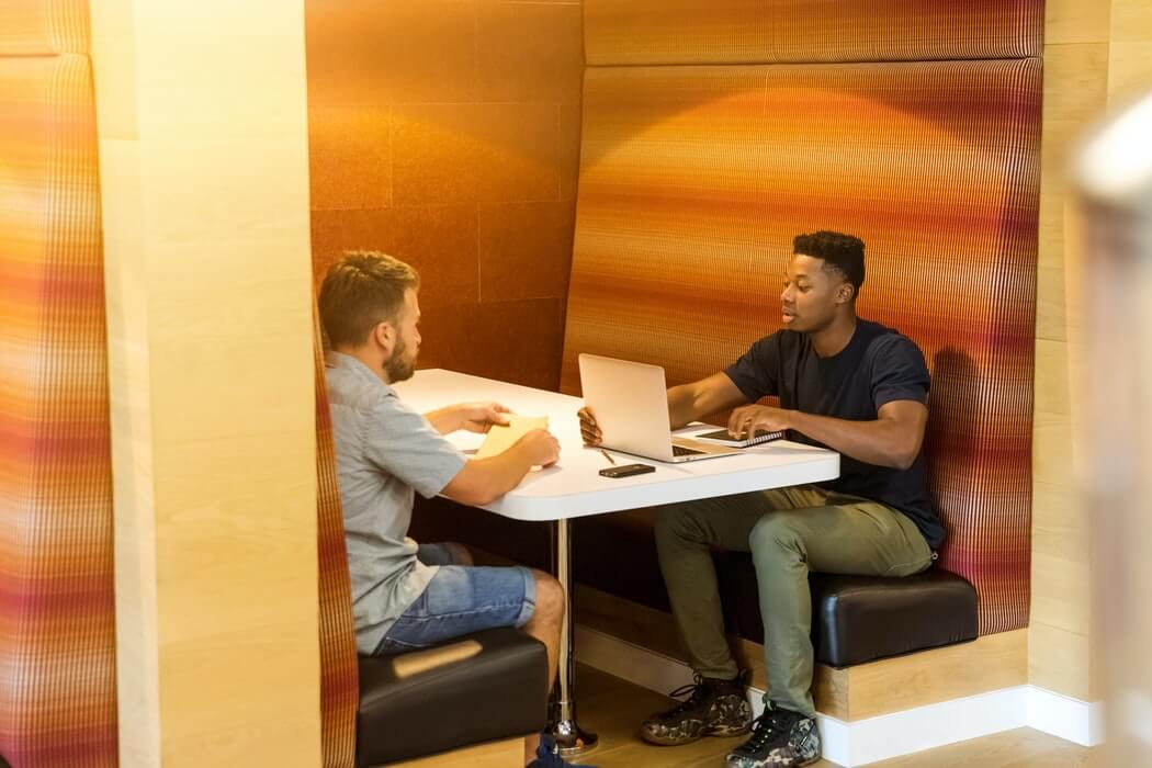 Homens trabalhando e conversando em posto de trabalho.