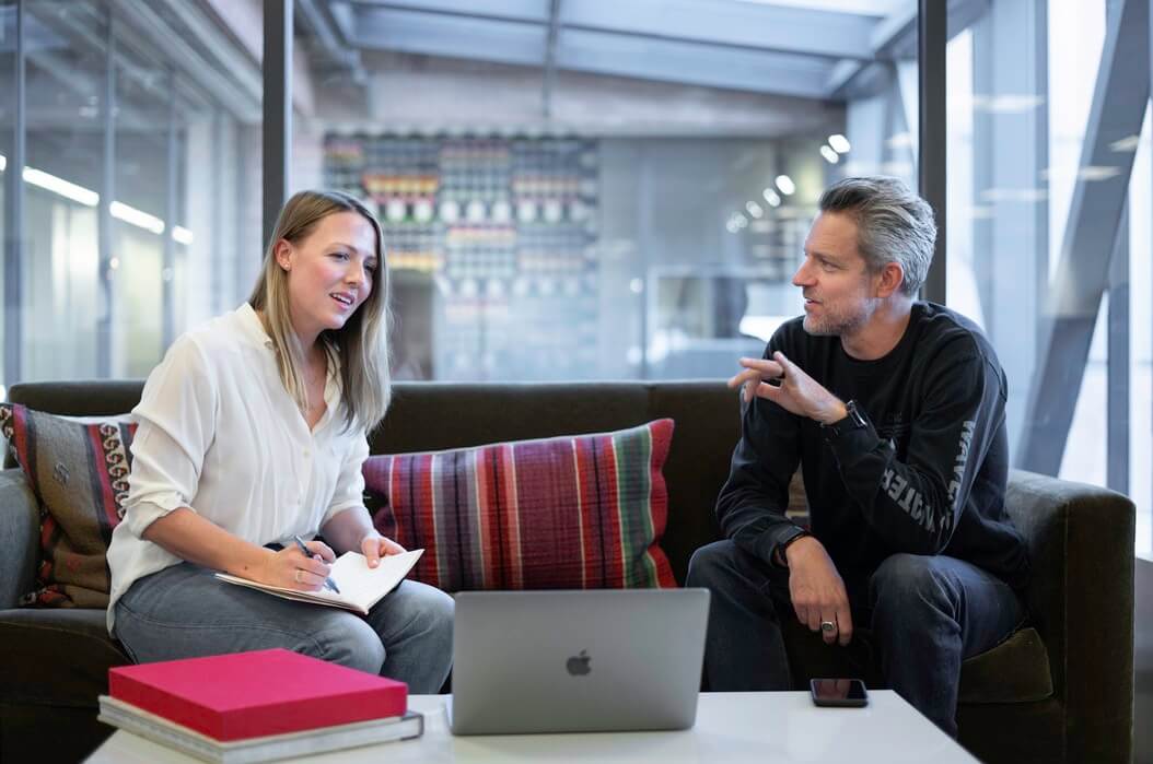 Homem e mulher conversando em reunião de empresa.