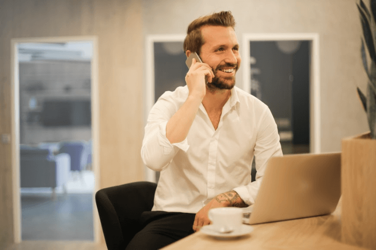 Homem de negócios ao telefone, marcando um teste de seu produto com clientes em potencial.