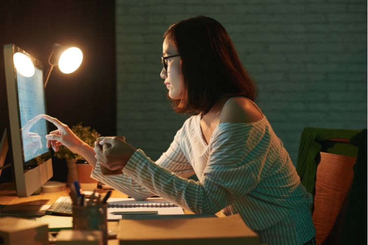 Mulher atenta à tela do computador, analisando dados.