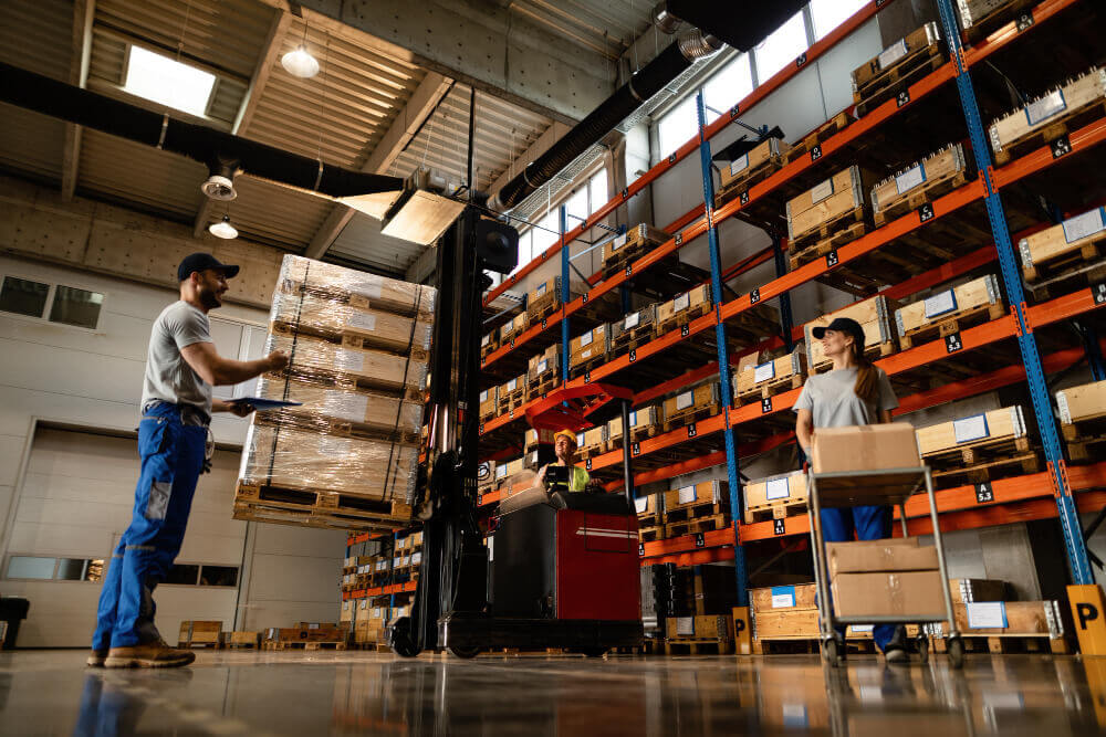Equipe trabalhando em um centro de distribuição com empilhadeira e prateleiras cheias de produtos, representando estratégias logísticas e operacionais para vender mais na Black Friday.