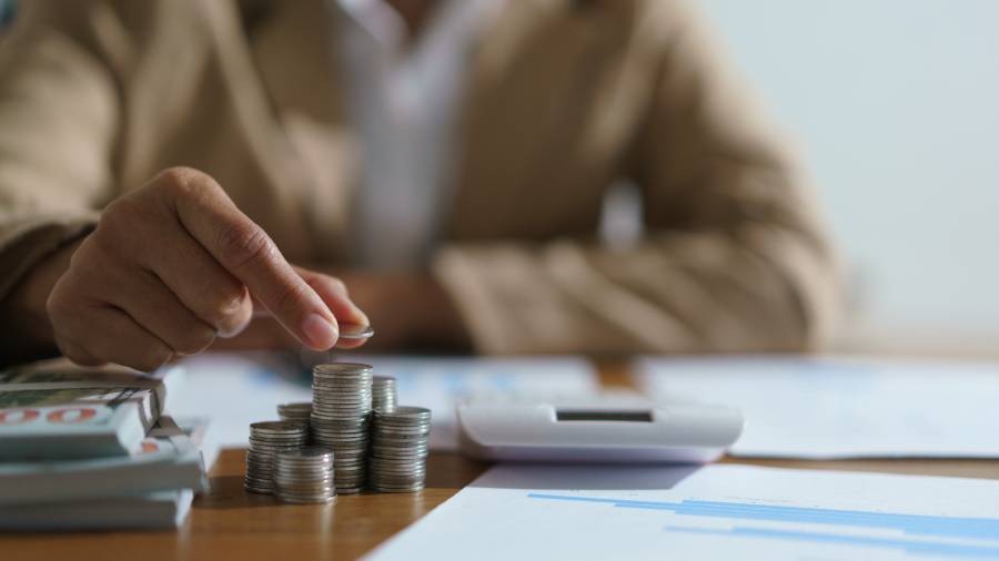 Empresário calculando valores de antecipação de recebíveis com moedas e planilha financeira