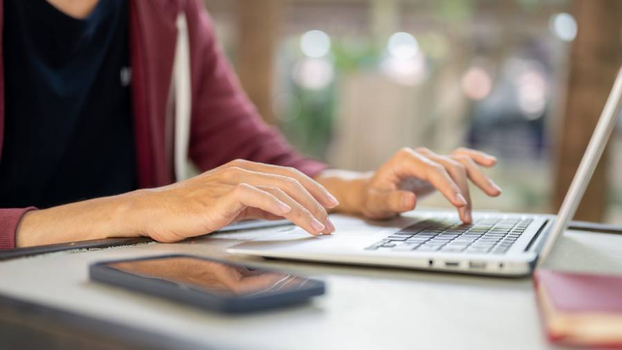 Pessoa digitando em notebook para conferir o repasse do iFood no painel financeiro da plataforma