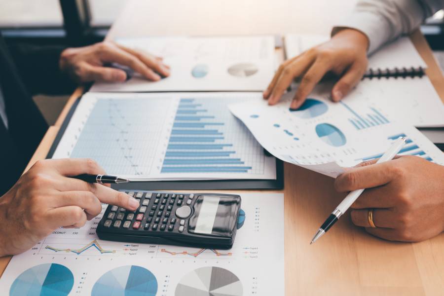 Pessoas analisando gráficos financeiros, representando conciliação bancária em marketplace.