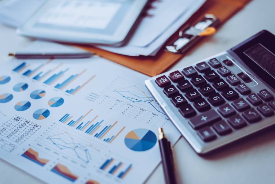 Calculadora sobre relatórios com gráficos coloridos, ilustrando gestão financeira e balanço patrimonial em marketplaces.
