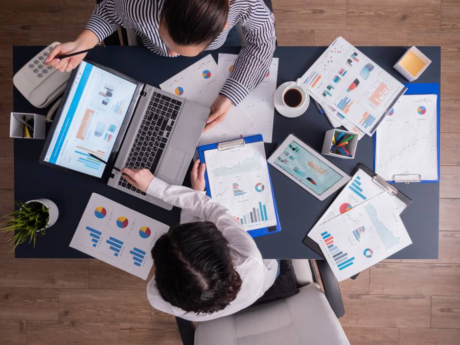 Equipe analisando relatórios e gráficos financeiros em reunião de conciliação de recebíveis de marketplace