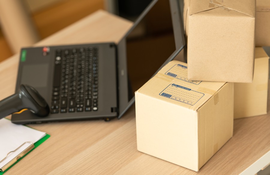 Caixas empilhadas e leitor de código de barras ao lado de laptop, cenário de operação com hub de integração marketplace