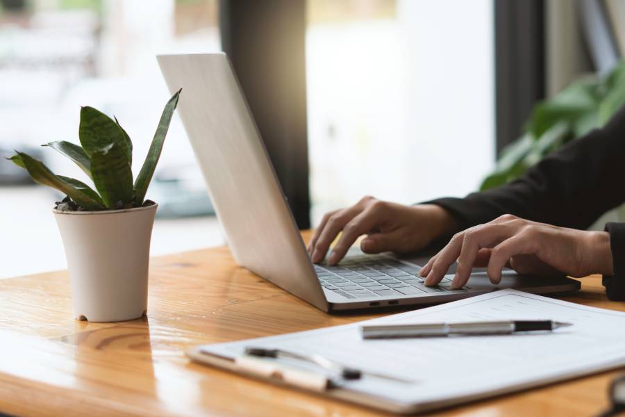 Pessoa digitando em laptop sobre mesa com prancheta, representando segurança da informação no e-commerce