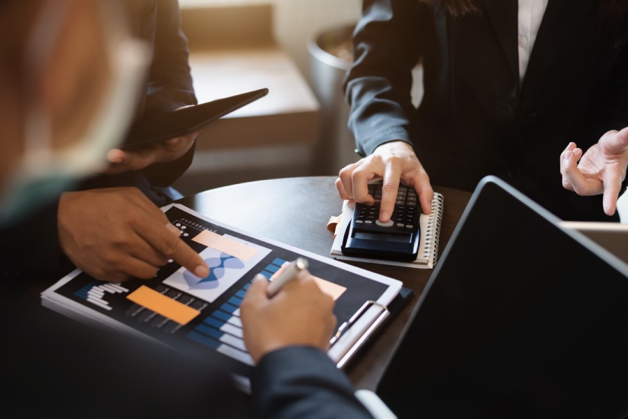 Equipe analisa gráficos e usa calculadora em reunião financeira para conferir o repasse Shopee de cada ciclo